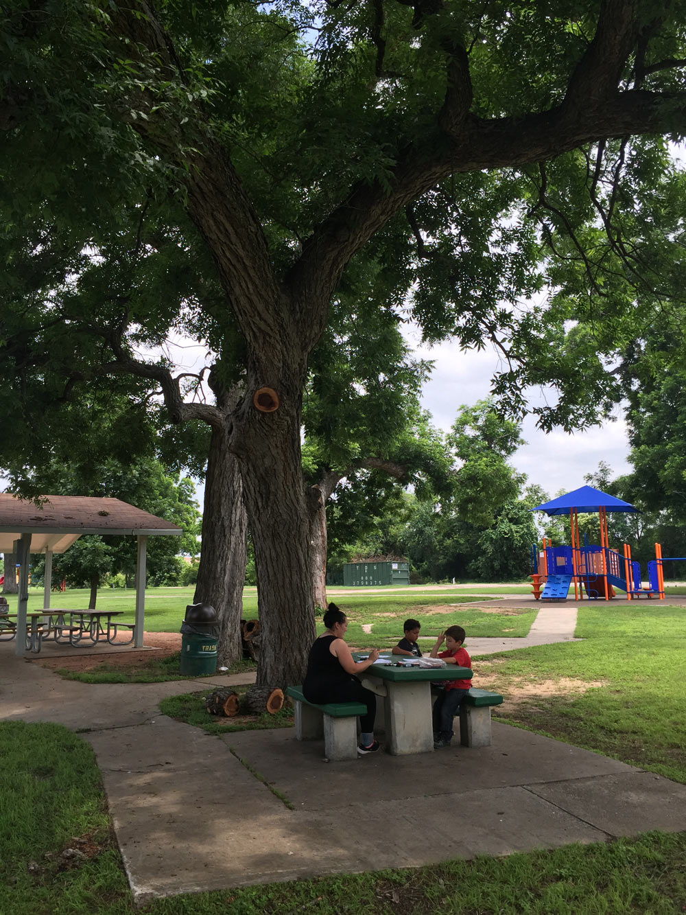 family on picnic table near playground and pavilion by dan pacatte